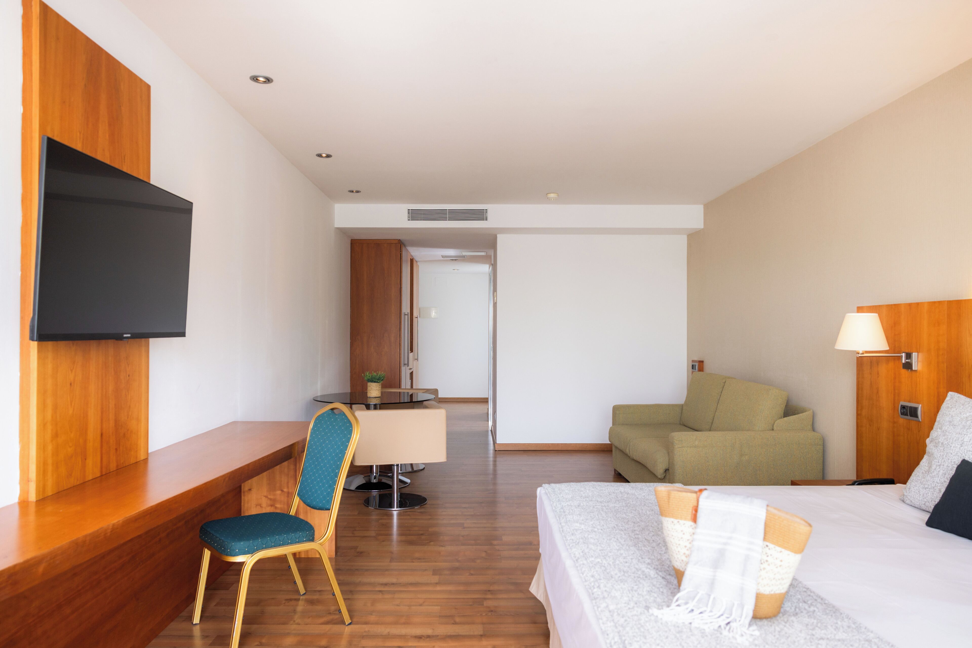 Een hotelkamer met een bed, bureau, stoel, televisie en een bank.