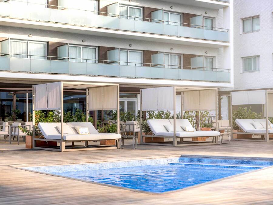 A rooftop pool area with lounge chairs and a glass balustrade.