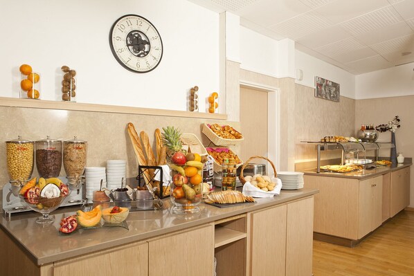 Un bufé de desayuno con diferentes alimentos y un reloj en la pared.