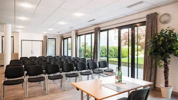 Una sala conferenze con file di sedie, un tavolo e un'ampia finestra con tende.