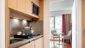 Uma cozinha moderna com micro-ondas embutido, máquina de café e uma pequena área de refeições com mesa e duas cadeiras.