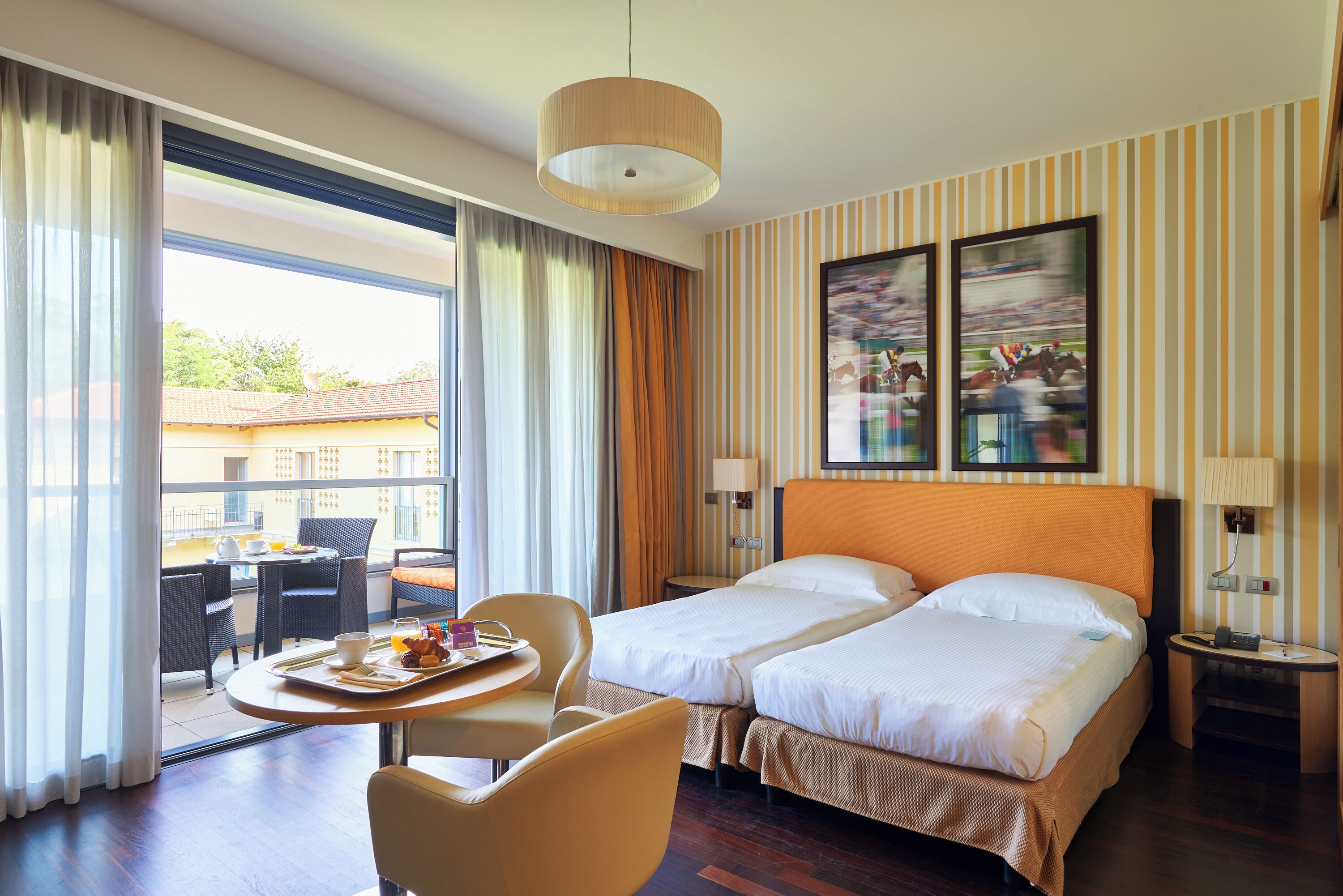 Habitación de hotel con dos camas, un comedor y vistas al exterior.
