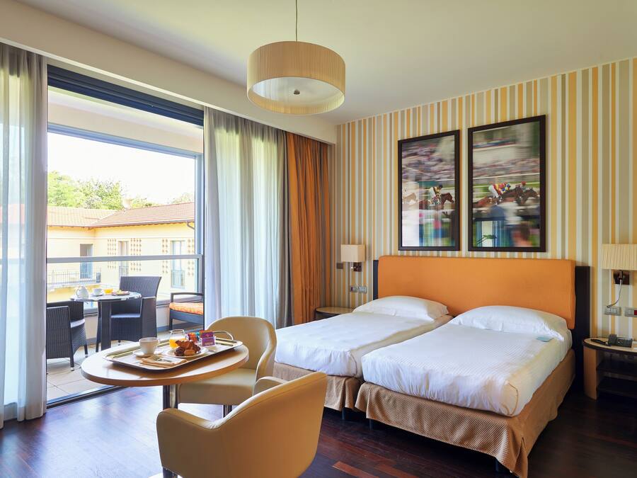 Een hotelkamer met twee bedden, een zithoek en uitzicht op de omgeving.