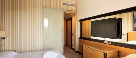 A hotel room with a bed, a TV, a dresser, and a mirror.