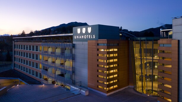 Un hotel moderno con un letrero llamativo, varios pisos y fachada de vidrio.