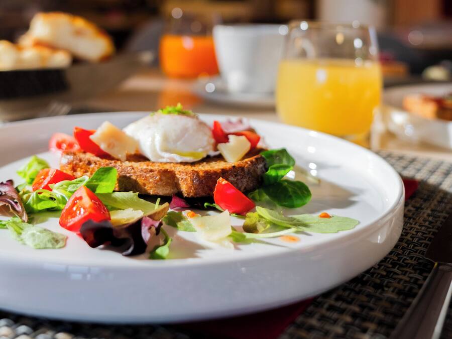 A breakfast plate with toast, eggs, and salad, a glass of orange juice, and a cup on a table.