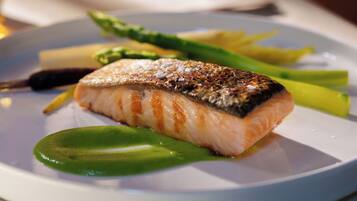 Een bord met gegrilde zalm, asperges en een citroenpartje.
