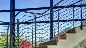 Una escalera de caracol con barandillas de metal y vistas a un jardín con follaje colorido.