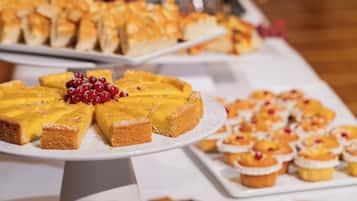 Un bufé con diversos postres, incluyendo un pastel de queso grande, mini tartas y cupcakes.
