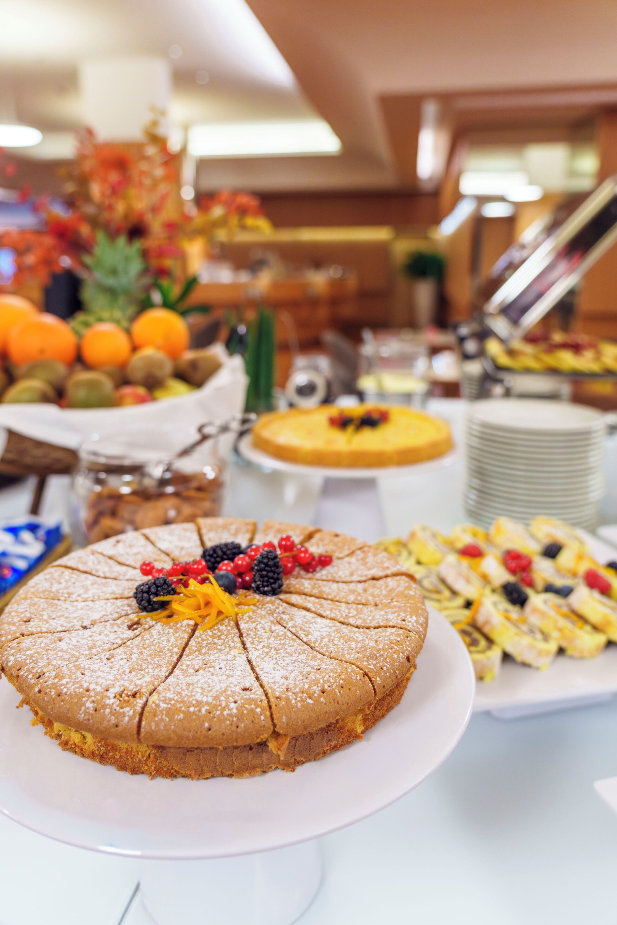 Une table de buffet proposant une variété de plats, notamment un gâteau décoré de fruits.