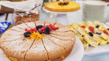 Une table de buffet proposant une variété de plats, notamment un gâteau décoré de fruits.