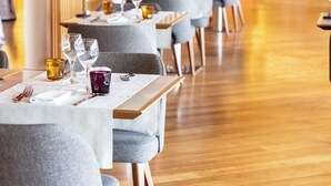 Un restaurante con mesas listas para comer, con piso de madera y una paleta de colores cálidos.
