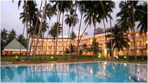 A hotel with a pool, palm trees, and a multi-story building with balconies. - Villa Ocean View (Wadduwa)