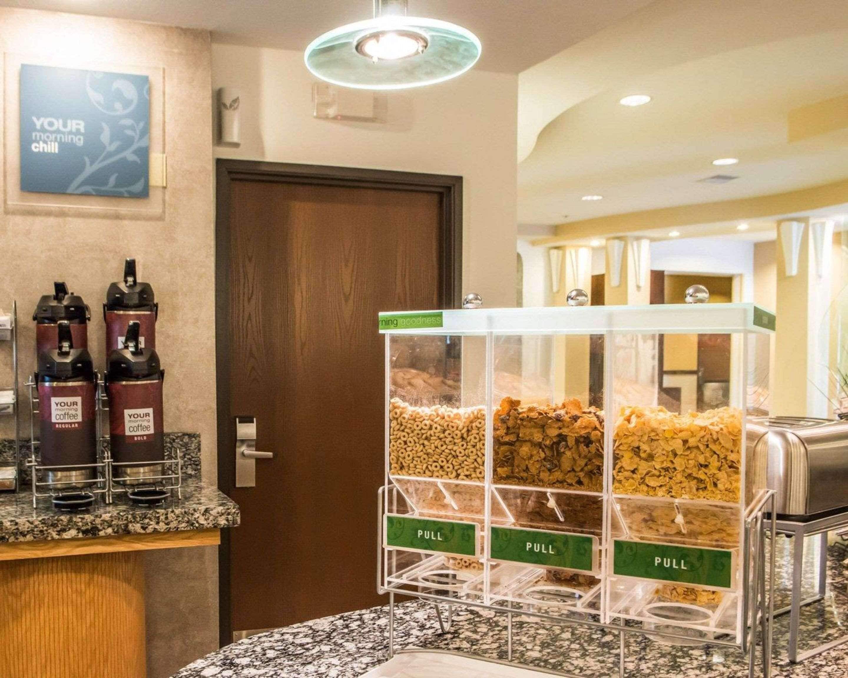 A coffee station with dispensers and a cereal dispenser with pull bins.