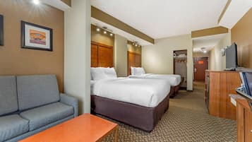 Habitación de hotel con sofá, dos camas, televisión y baño a la vista.