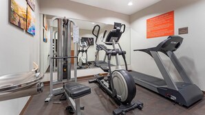 A fitness center with cardio equipment, a weight machine, and a mirrored wall.
