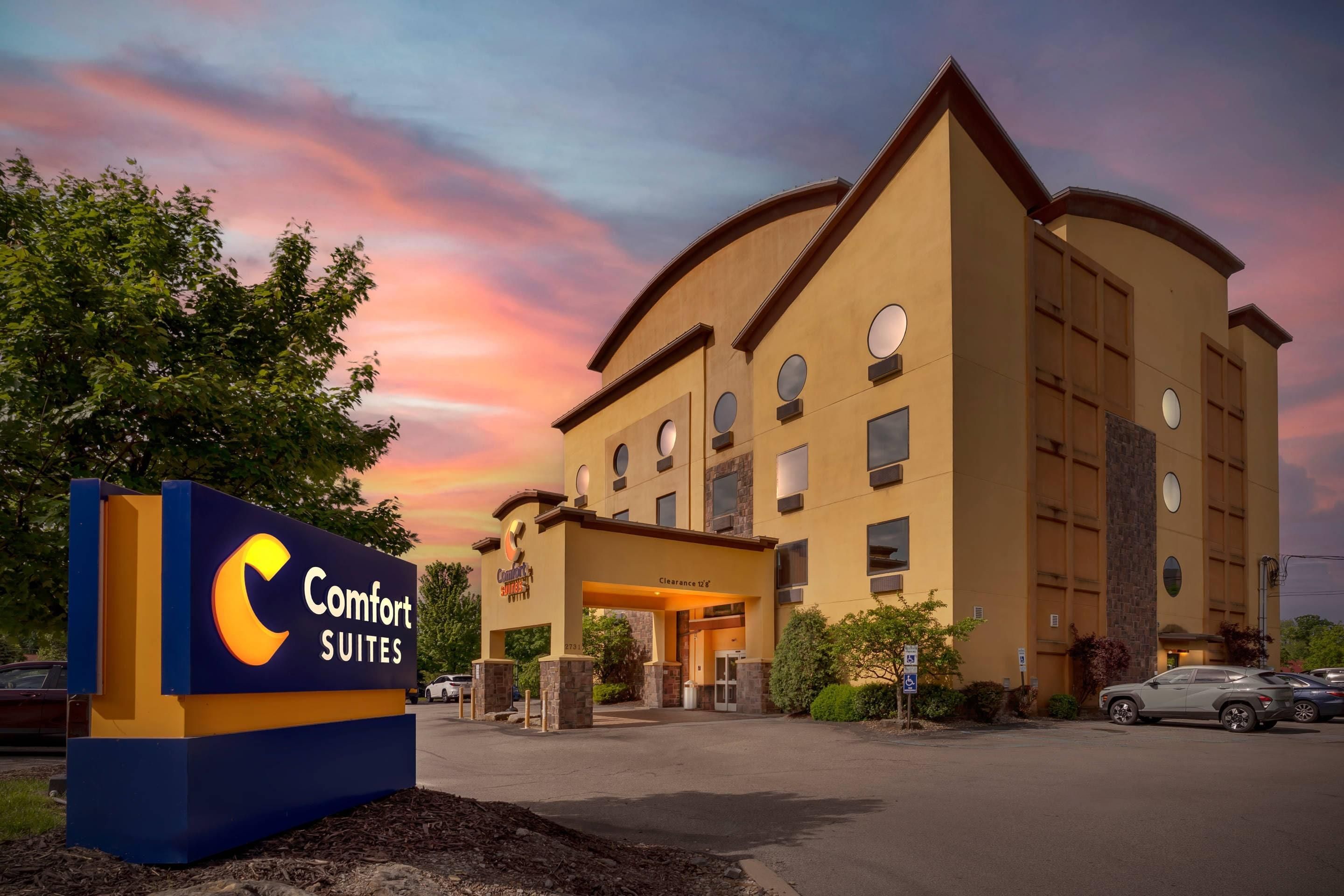Un hotel Comfort Suites con un cartel, aparcamiento y cielo despejado.