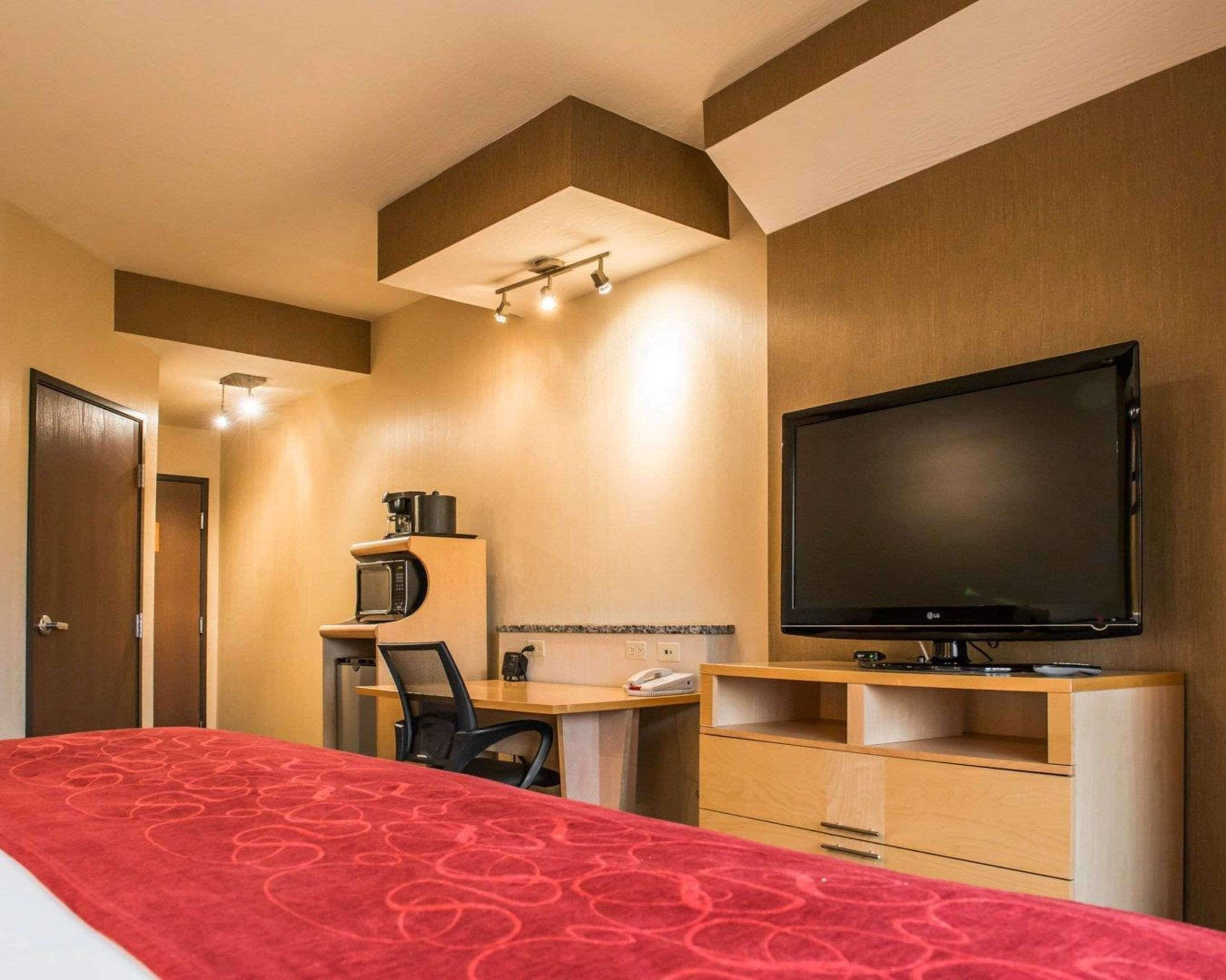 A hotel room with a bed, a desk, a television, and a microwave.