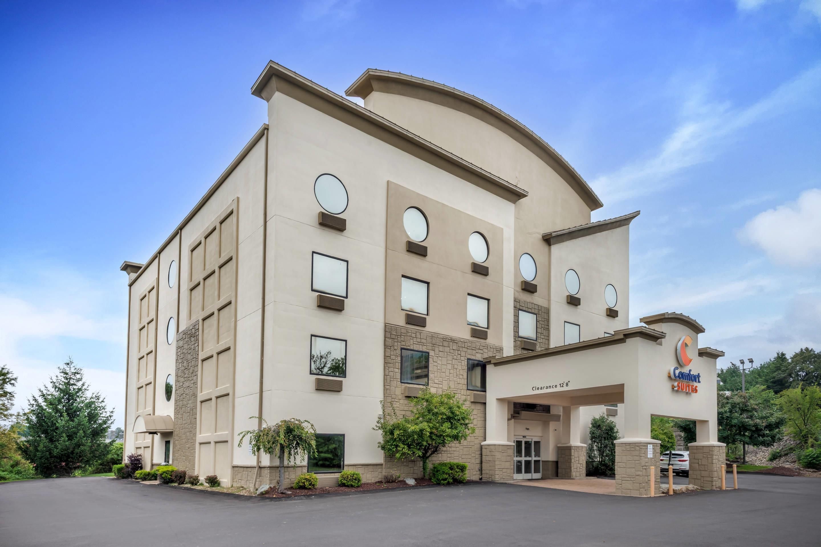 Et hotel med flere etager, fladt tag, store vinduer og et skilt der viser 'Comfort Suites'.