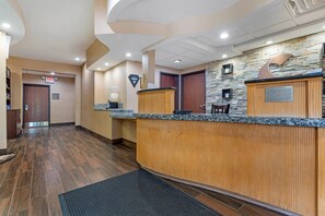 A reception area with a wooden counter, stone wall, and a sign indicating a guest room. - Comfort Suites Monroeville - Pittsburgh East (Monroeville)