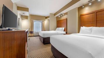 A hotel room with two beds, a TV, and a desk.