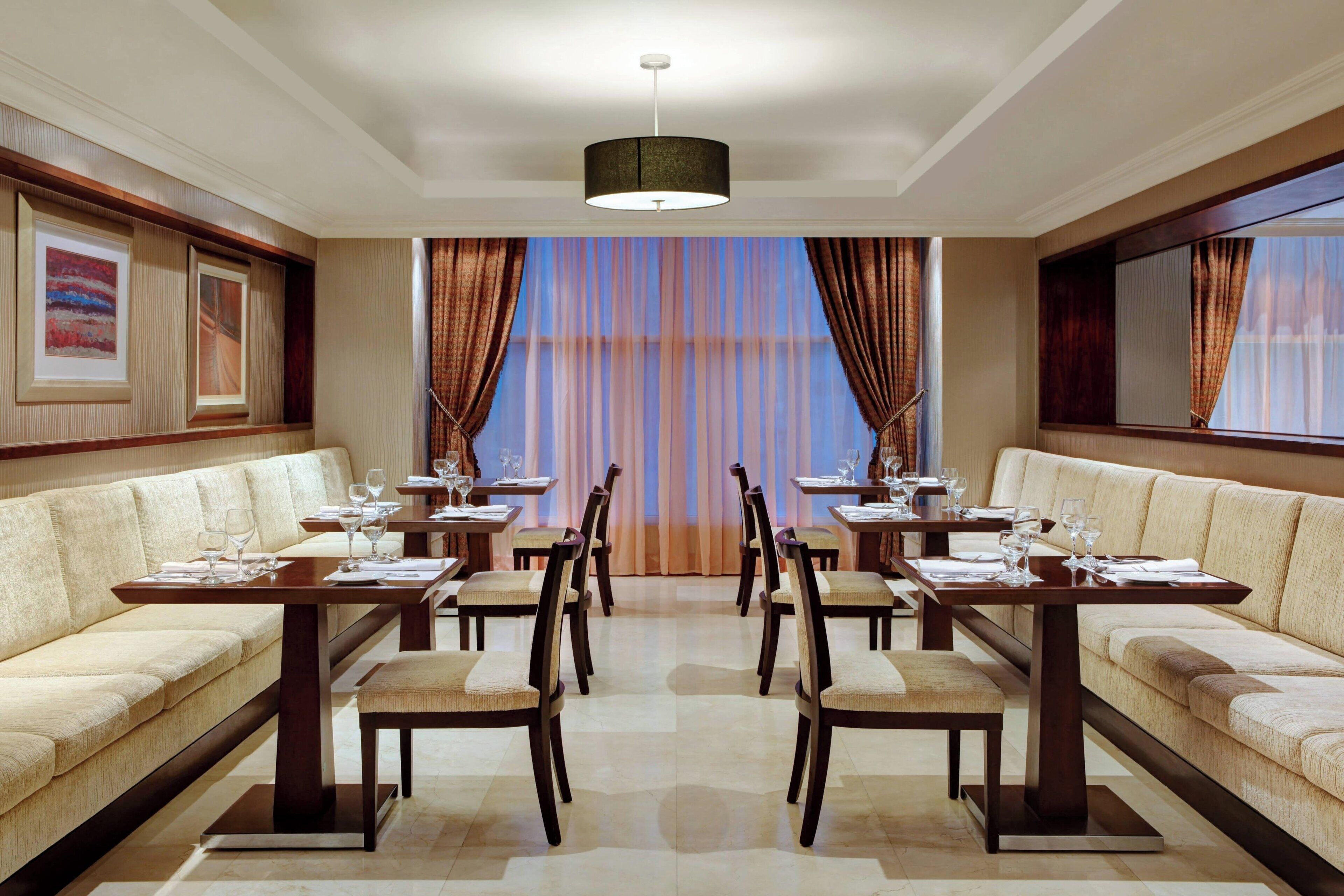 A dining area with a central table, chairs, and sofas.