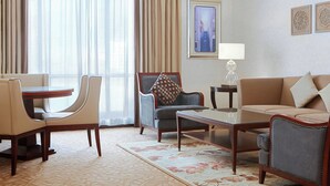 A hotel room with a dining area, a sofa, a chair, and a lamp. - Le Meridien Towers Makkah (Makkah)