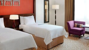 A hotel room with two beds, a chair, a nightstand, a lamp, and a mirror. - Le Meridien Towers Makkah (Makkah)