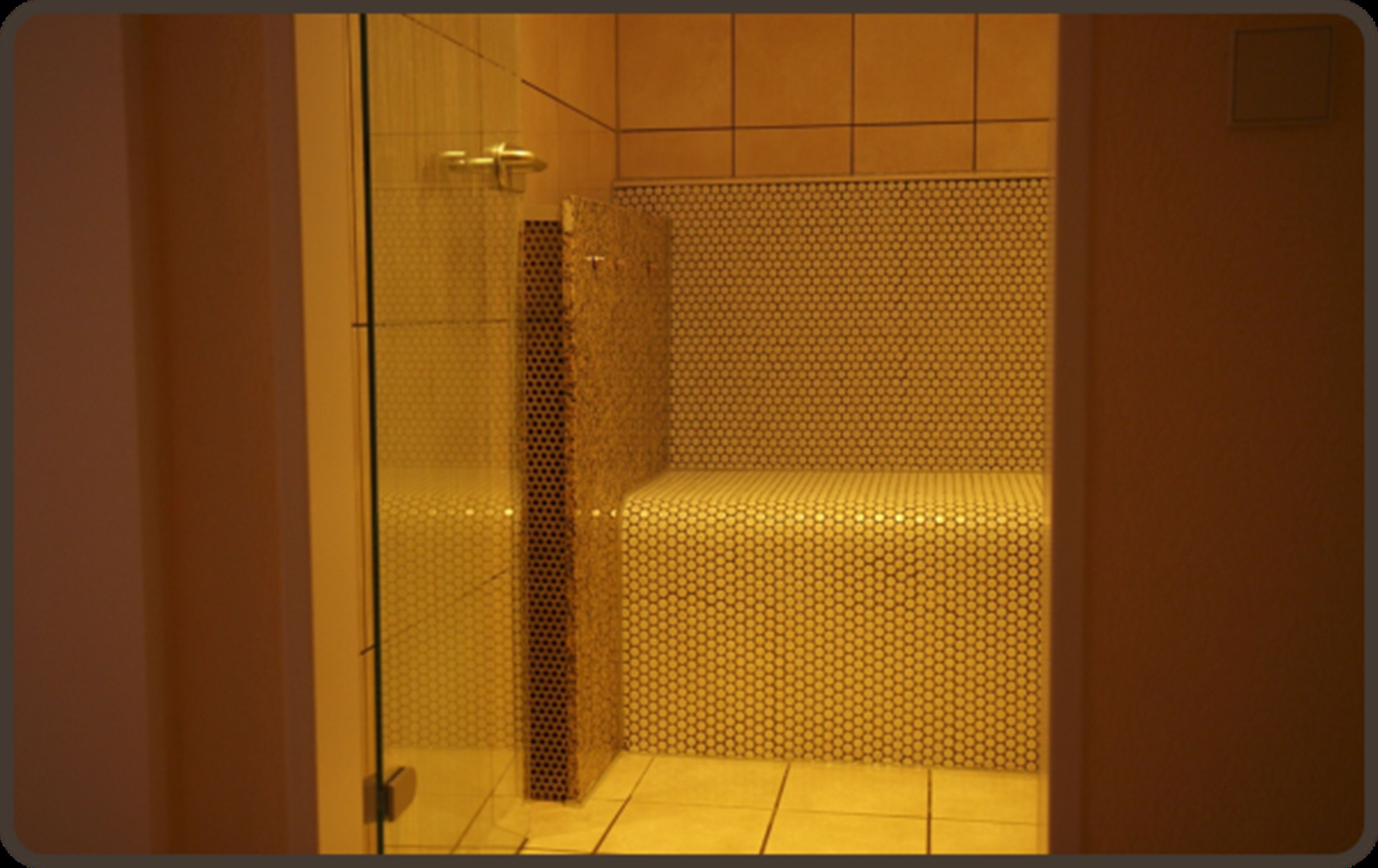 Eine gläserne Dusche mit gefliestem Boden und einem gemusterten Wandbild.