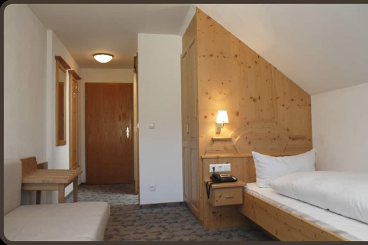 Una habitación con una cama de madera, una mesita de noche, una lámpara y un escritorio pequeño con una silla.
