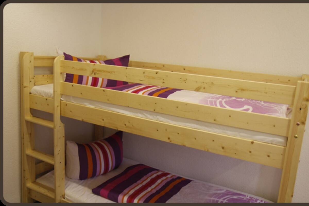 Una cama litera con dos niveles, cada uno con una almohada y una manta a rayas.