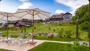 A hotel with outdoor seating, a swimming pool, and a landscaped garden. - Parkhotel Waldlust (Häusern)