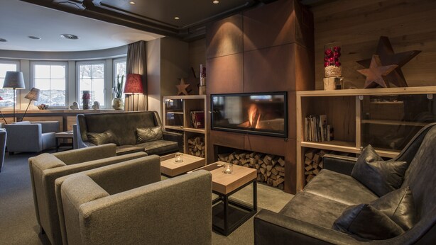 A modern living room with a fireplace, comfortable seating, and a television. - Hotel Valentin (Soelden)