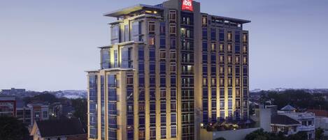 A multi-story hotel with a prominent 'ibis' sign, large windows, and a modern architectural design.