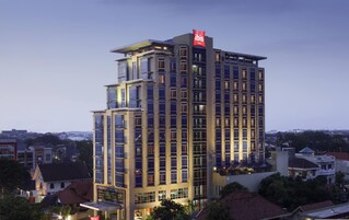 A multi-story hotel with a prominent 'ibis' sign, large windows, and a modern architectural design.