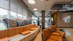 A modern waiting area with a wooden bench, orange cushions, and leather chairs.
