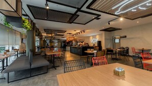 A modern cafe with wooden tables and chairs, a bar area, and a seating area with a bench.