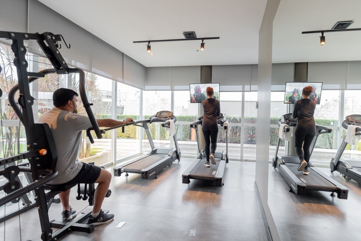 A gym with treadmills, weight machines, and a large mirror.