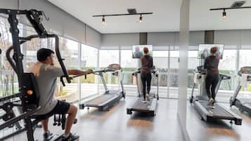 A gym with treadmills, weight machines, and a large mirror.