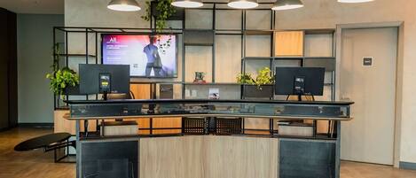 Un mostrador de recepción con una pantalla de televisión, dos monitores y una encimera de madera.