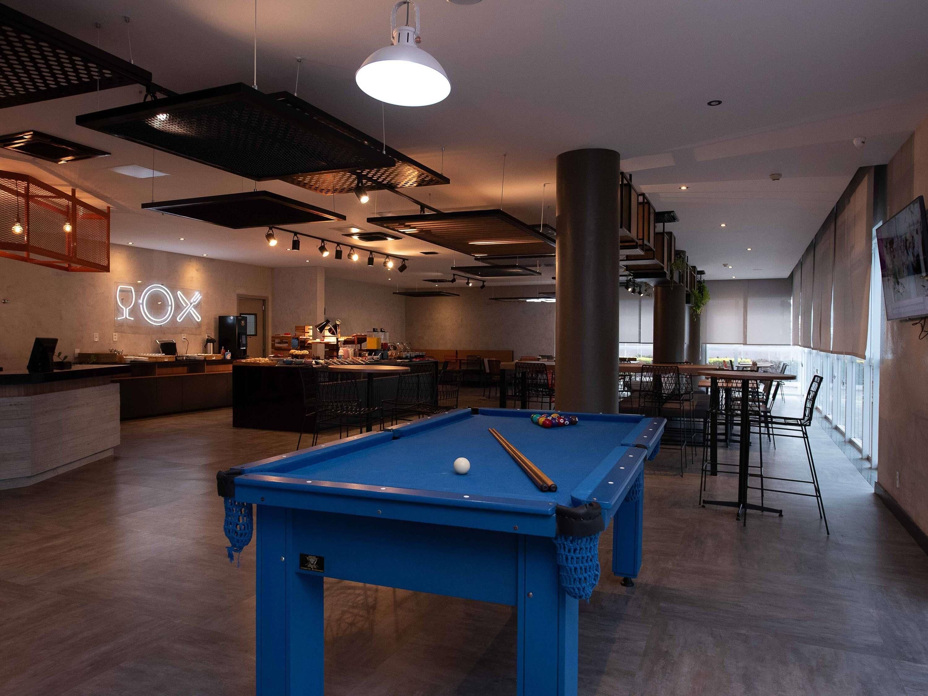 Ein Billardtisch in einem modernen Loungebereich mit Bar und Sitzgelegenheiten.