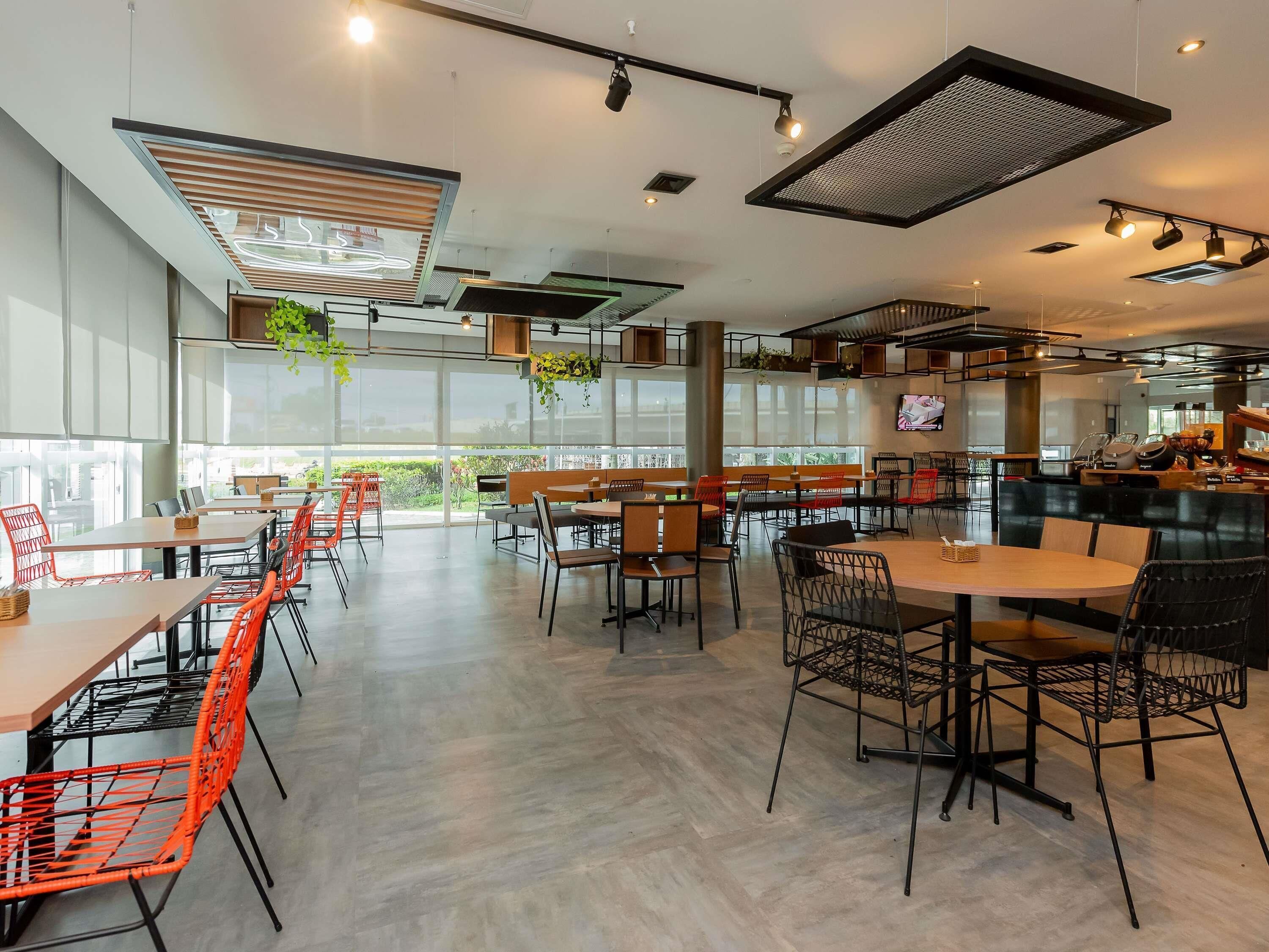 A modern cafe interior with high ceilings, large windows, and a variety of seating arrangements including tables and chairs.