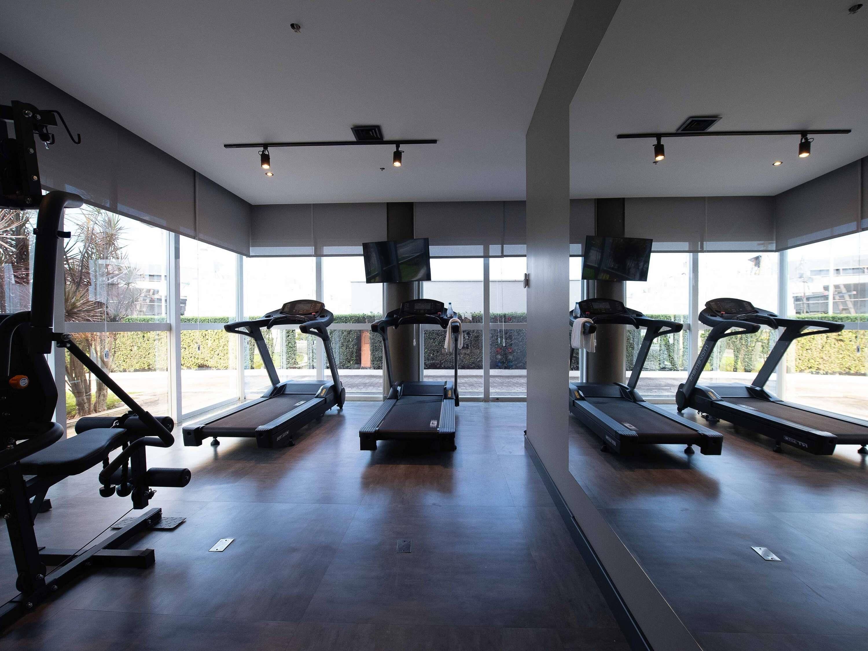 A gym with treadmills, weight machines, and large windows.