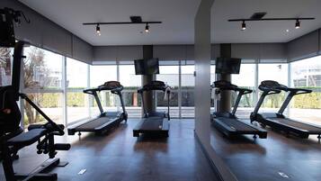 A gym with treadmills, weight machines, and large windows.