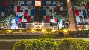A hotel with a checkered facade, illuminated signage, and well-maintained landscaping.