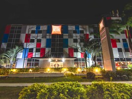 Un hotel con fachada a cuadros, señalización iluminada y jardines bien cuidados.
