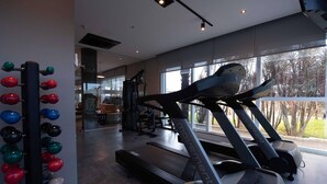 A gym with treadmills, a weight machine, and a ball rack.