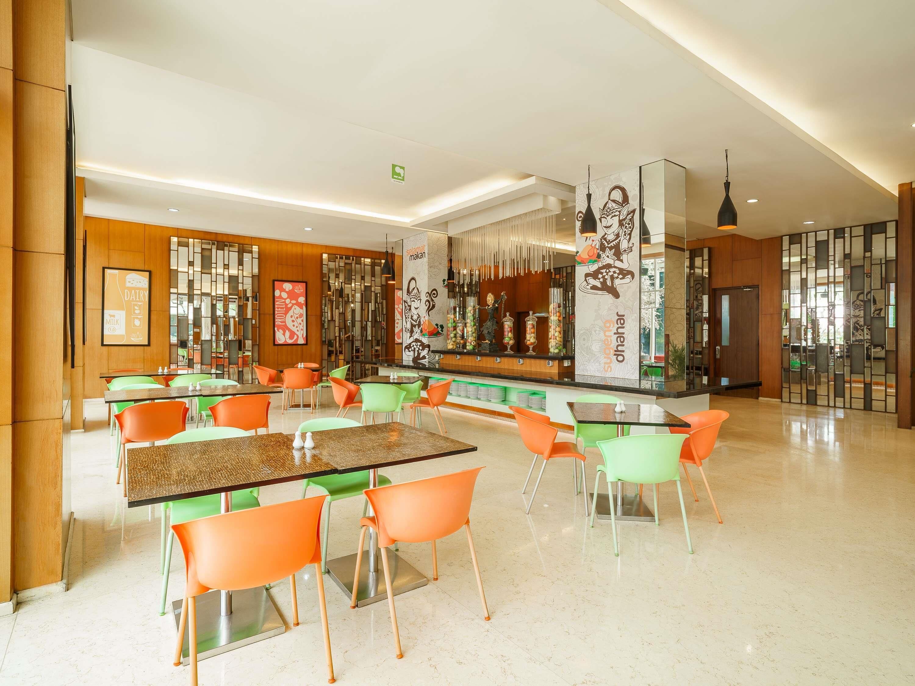 A modern restaurant with a bar area, multiple seating options including tables and chairs, and decorative elements like wall art and a vertical display.