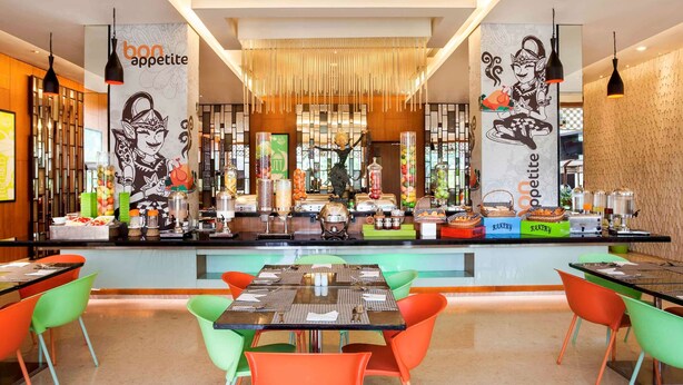 Un restaurante moderno con una barra central, sillas de colores y una variedad de dispensadores de comida y bebida.