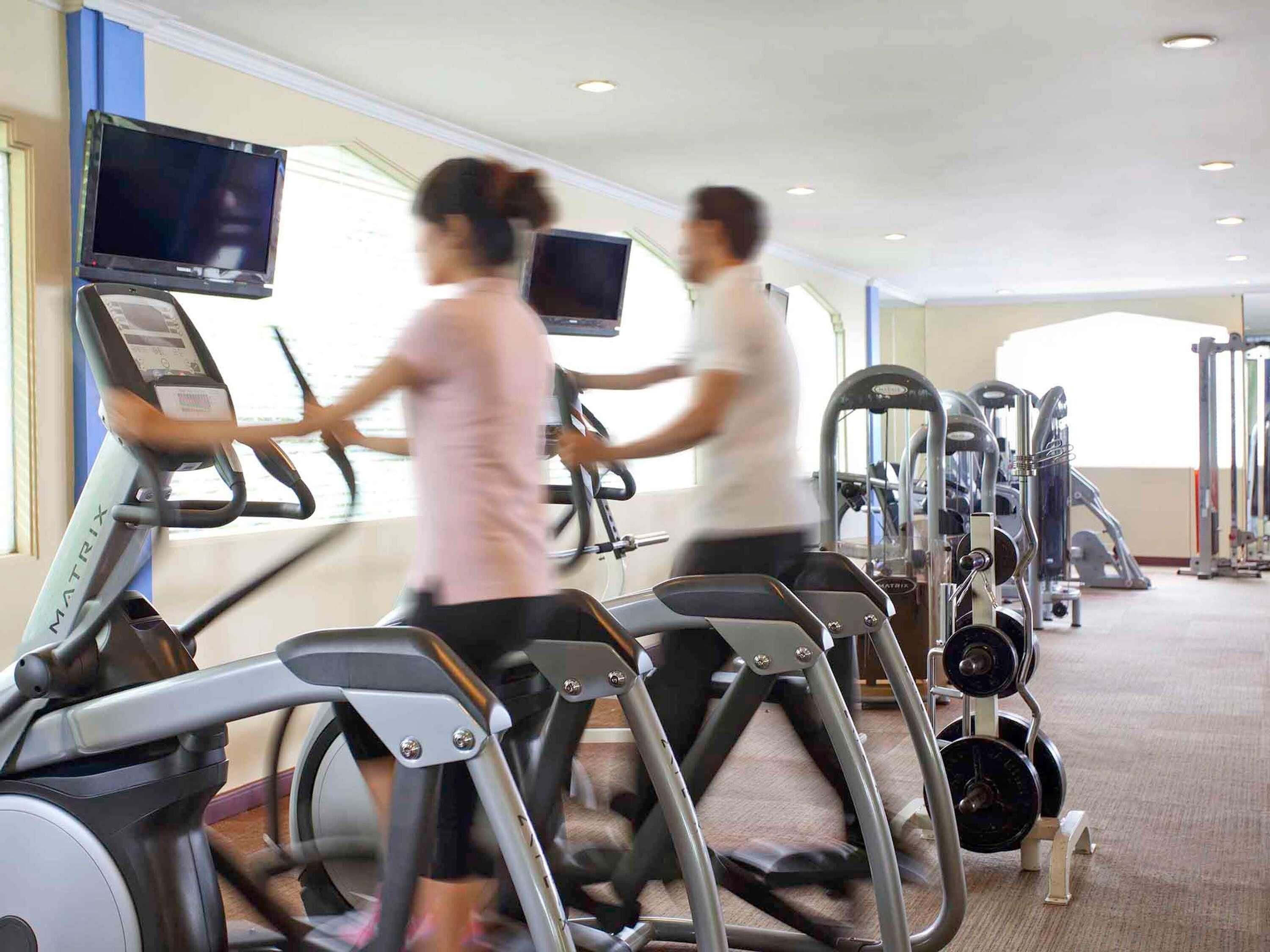 Un gimnasio con cintas de correr, máquinas de pesas y una pantalla de televisión.